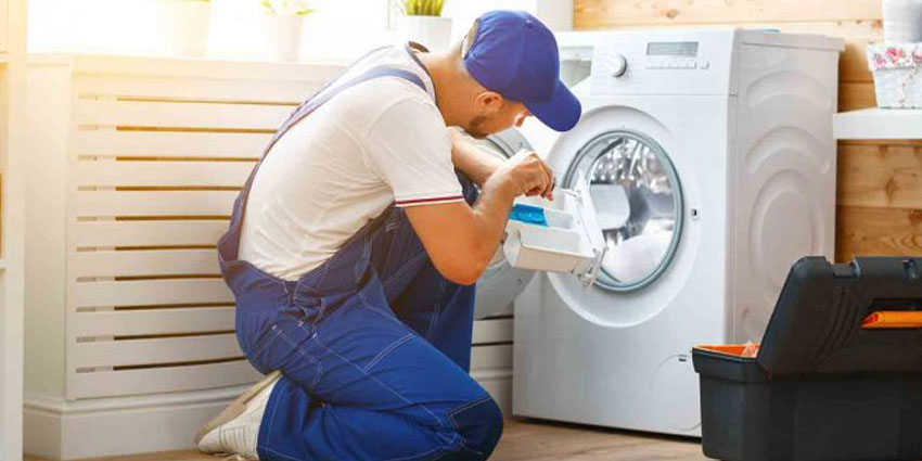 Teknisyen çamaşır makinesi tamir ediyor